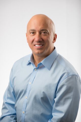 A man smiling at the camera with white background