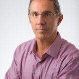 A man wearing a pink shirt, smiling at the camera