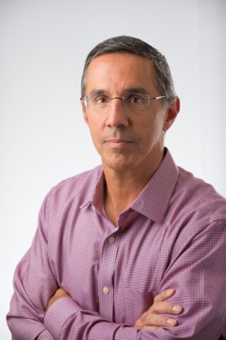 A man wearing a pink shirt, smiling at the camera